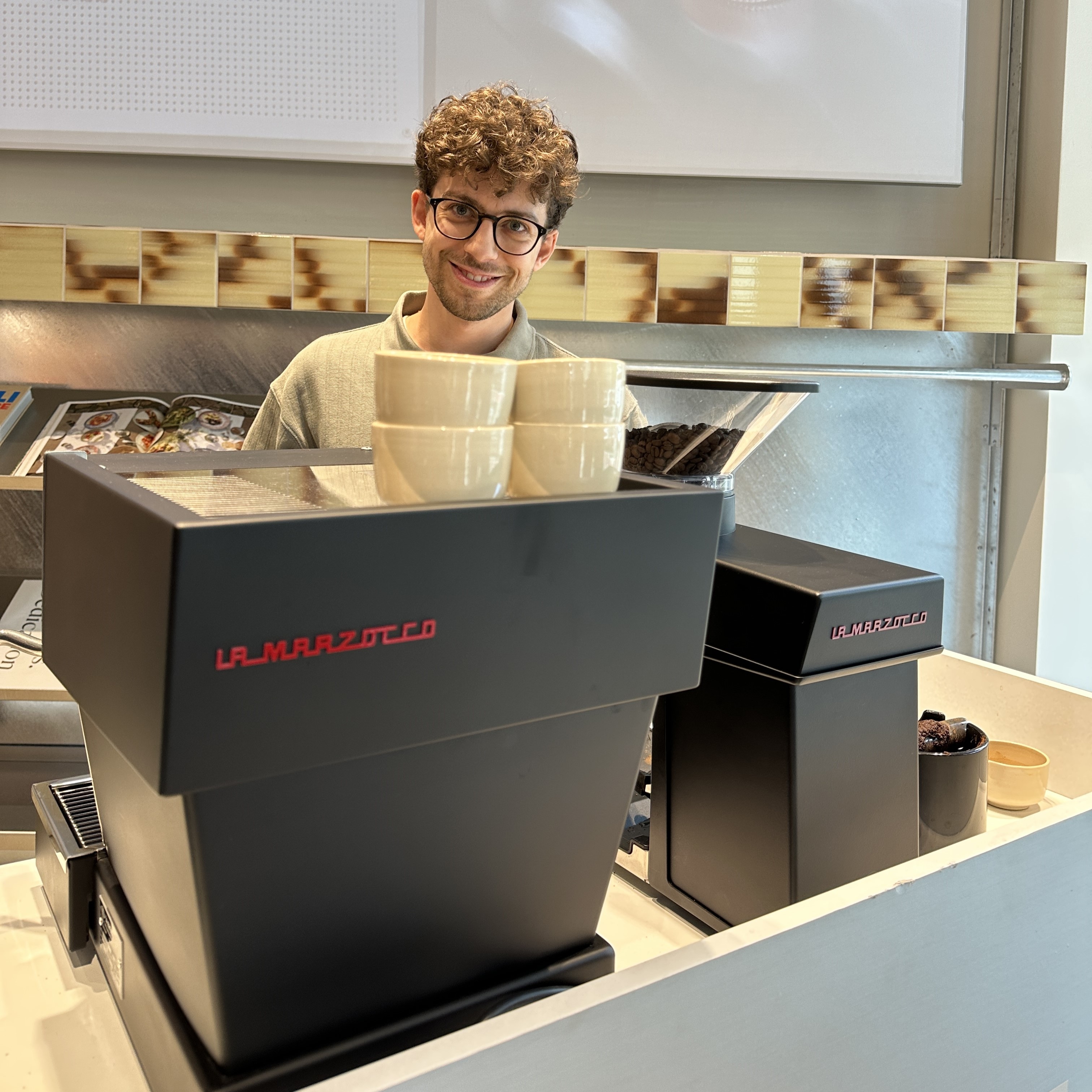 Tamir Neffgen behind a La Marzocco Linea espresso machine in a café